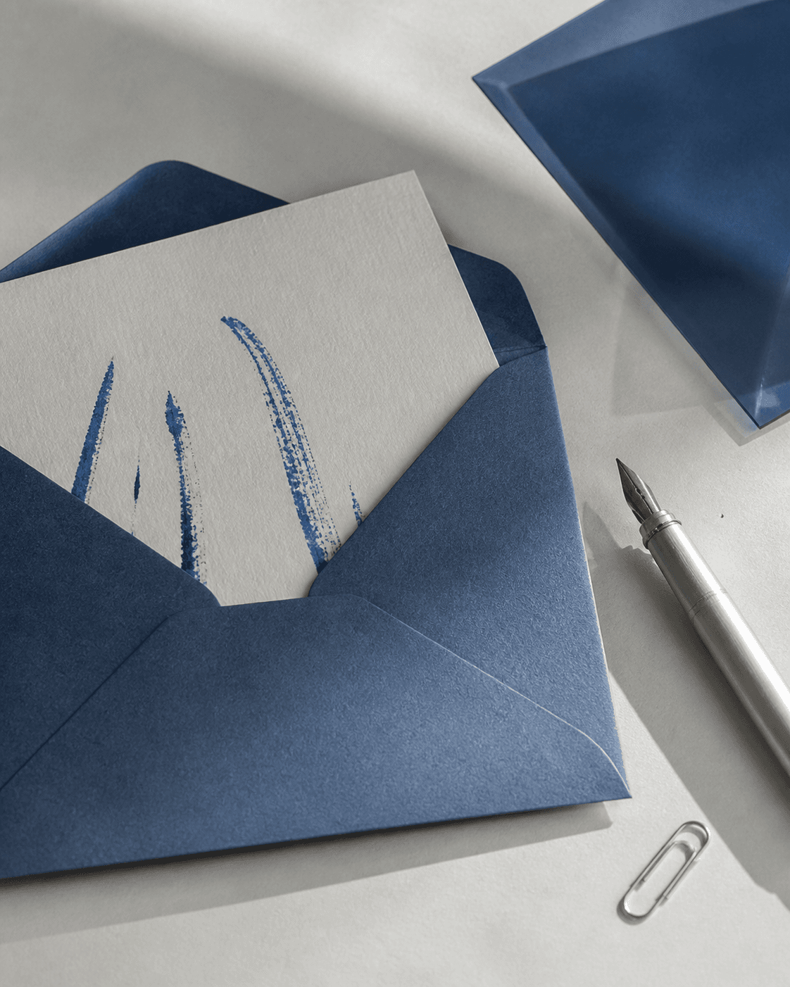 Lettre dans une enveloppe bleue posée sur une table avec un stylo plume